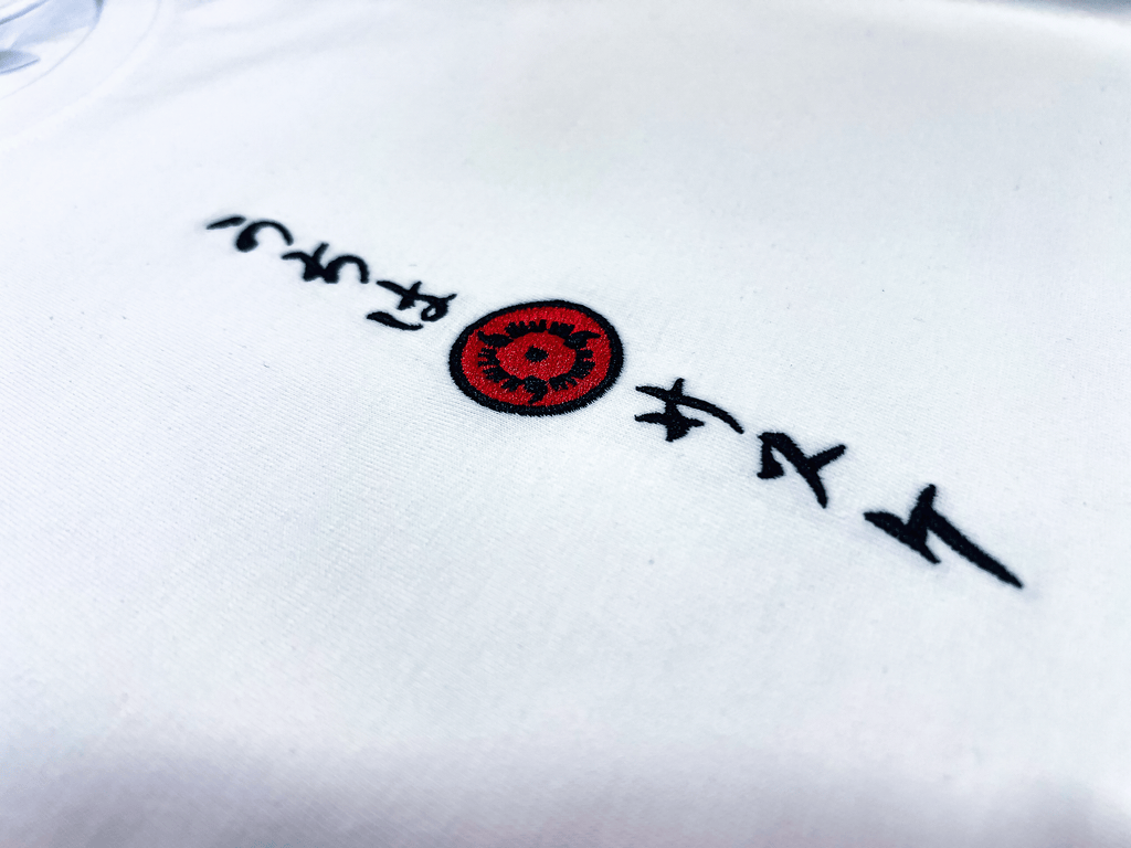 Zoom broderie verticale calligraphie Uchiha Sasuke et Sharingan rouge sur blanc – T-Shirt Naruto Shippuden™ PROJO